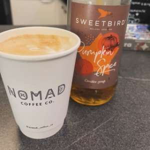 A Nomad cup next to a bottle of pumpkin spice syrup