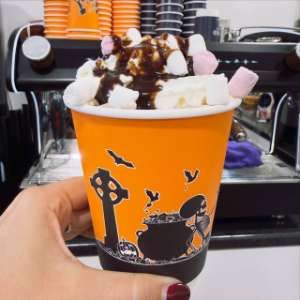 A Halloween cup of hot chocolate topped with cream, marshmallows and chocolate sauce
