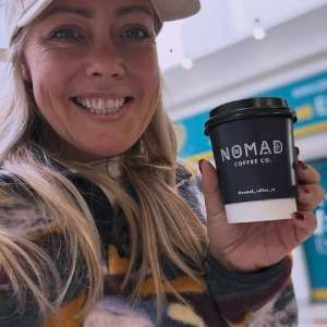 A smiling customer holding a navy Nomad cup