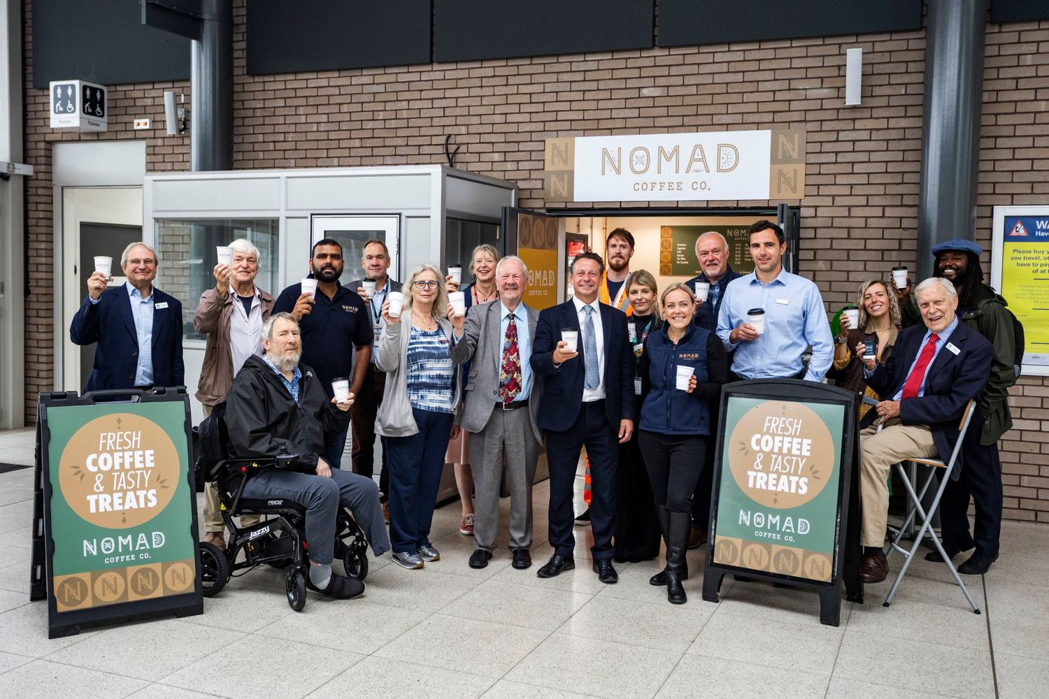 Guests, councillors, GWR staff and Nigel Huddleston MP raising Nomad cups outside the Parkway café at its official opening